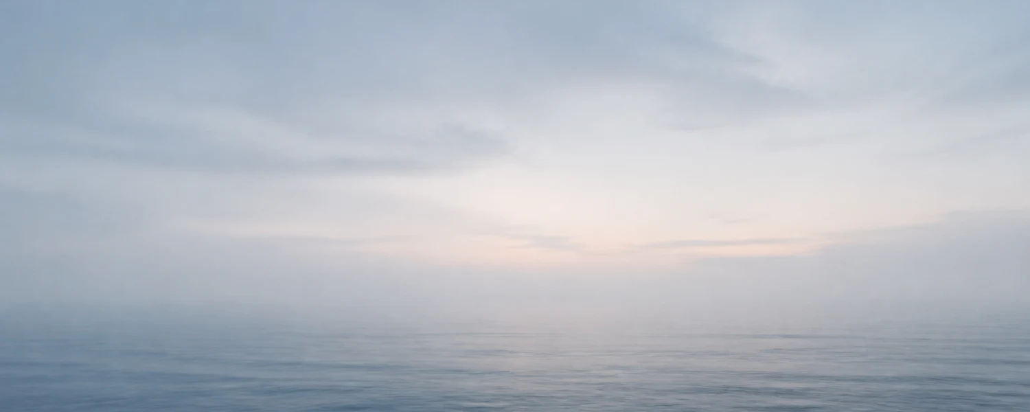 Calm misty ocean horizon at dawn in soft blue-gray tones